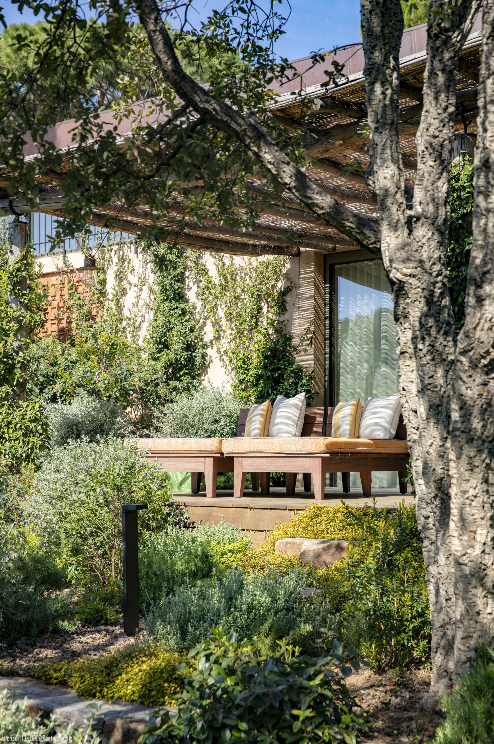 Coin lounge sous pergola en vigne vierge Coin lounge sous pergola en bois couverte de vigne vierge dans un jardin par MR Paysage