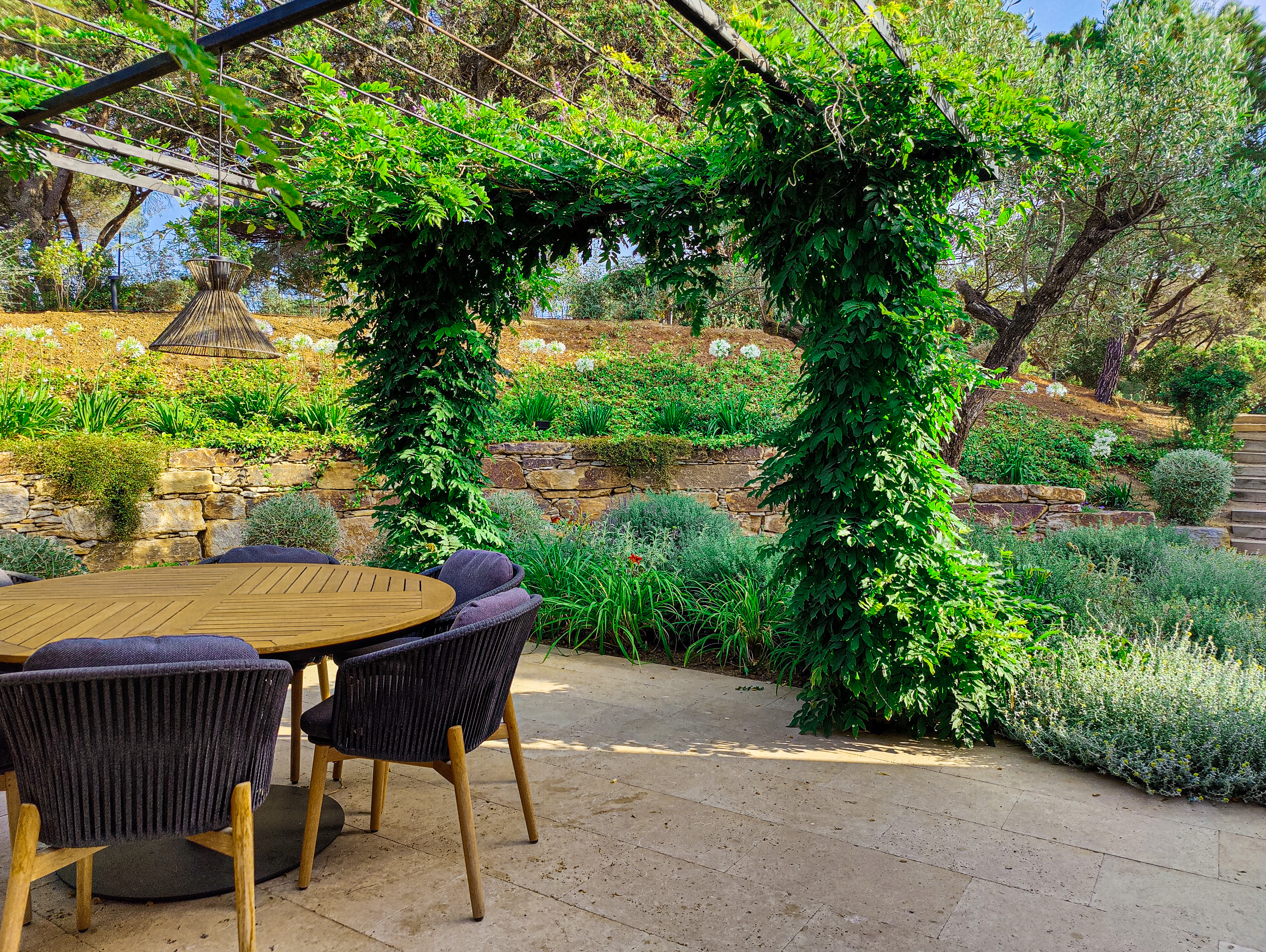 Pergola en métal et arche de glycine Pergola en métal noir avec glycine et coin repas dans un jardin de villa par MR Paysage
